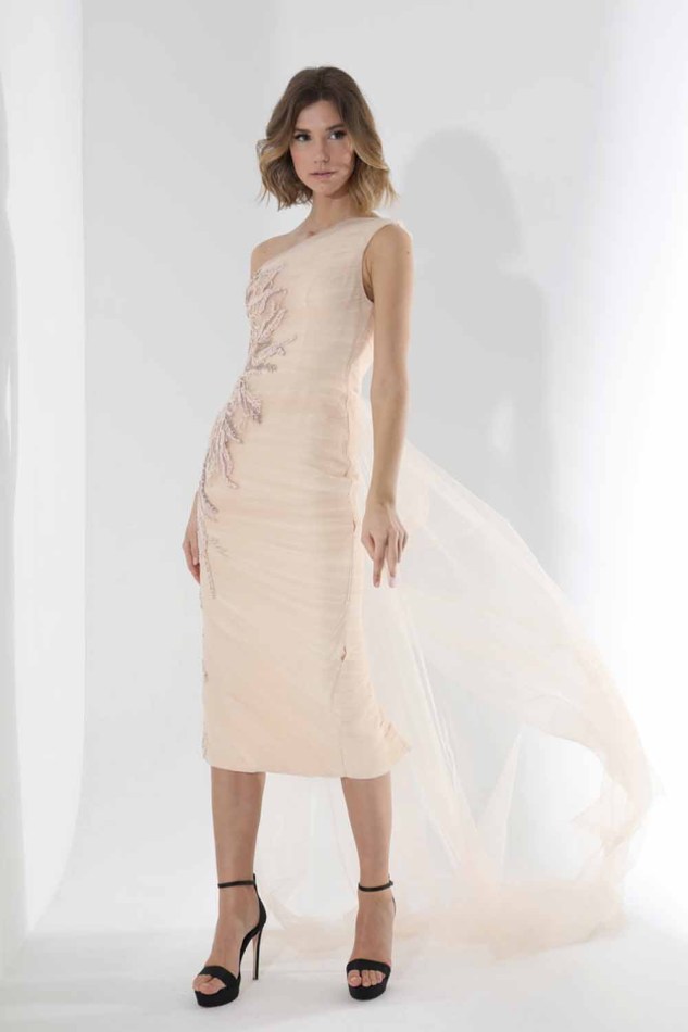 Φόρεμα μίντι τούλινο με ουρά στο πλάι . Έχει έναν ώμο, σούρες κατά μήκος του φορέματος και ασημί κέντημα στην μία πλευρά. 